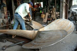 Fabrication artisanale d’un bateau dans un chantier naval avec artisans au travail